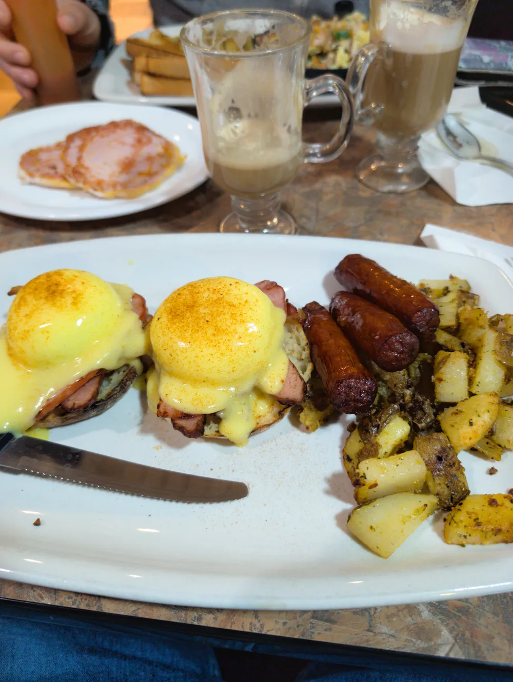 Eggs benedict on a plate with home fries