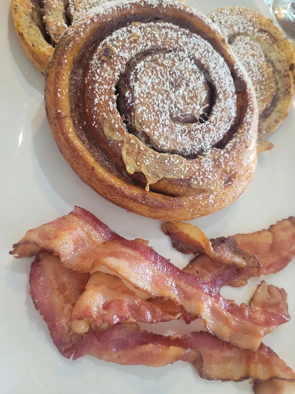 A cinnamon bun with a side of bacon