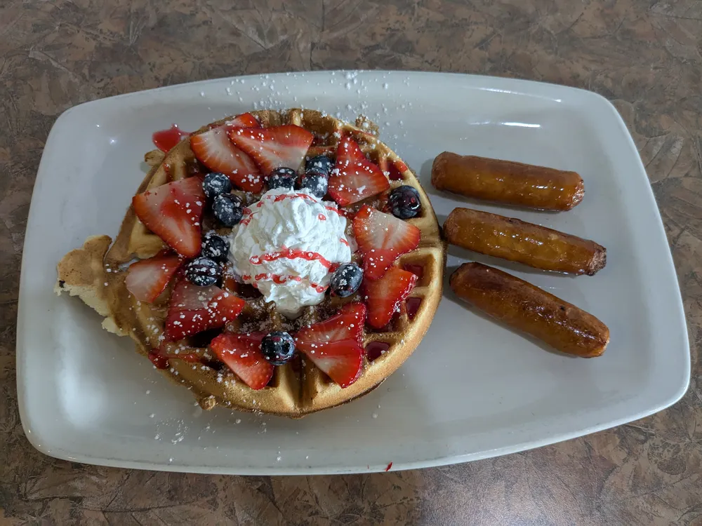 A Belgian waffle with berries and whipped cream